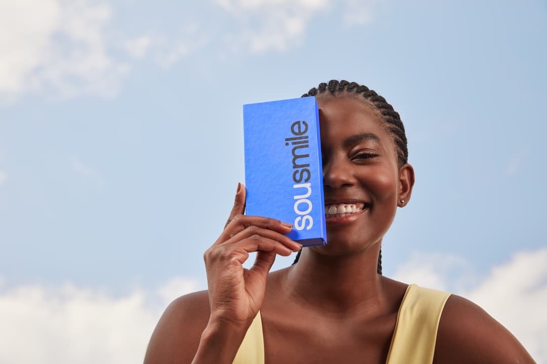 menina negra com caixinha de clareamento dental