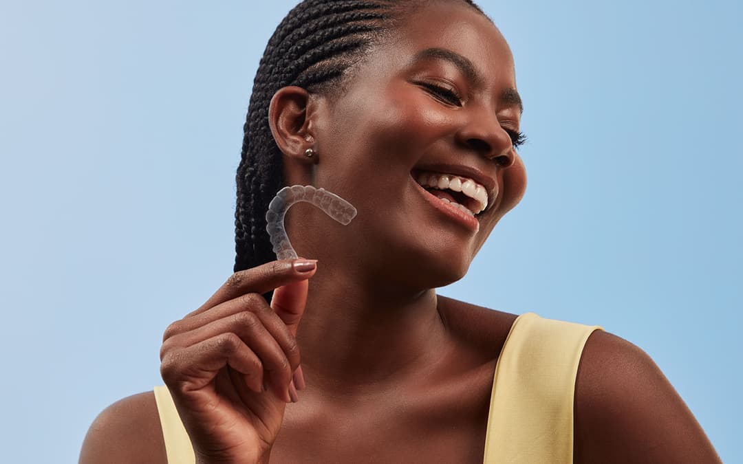 mulher sorrindo em frente ao céu segurando um alinhador