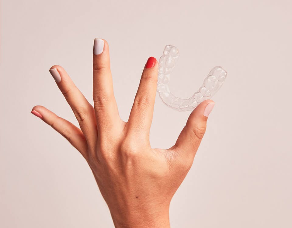 Uma mão segurando um aparelho transparente SouSmile