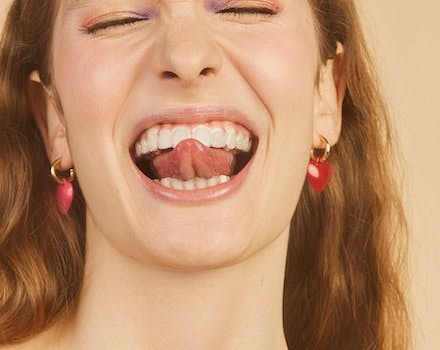 mulher sorrindo com a ponta da lingua para fora da boca