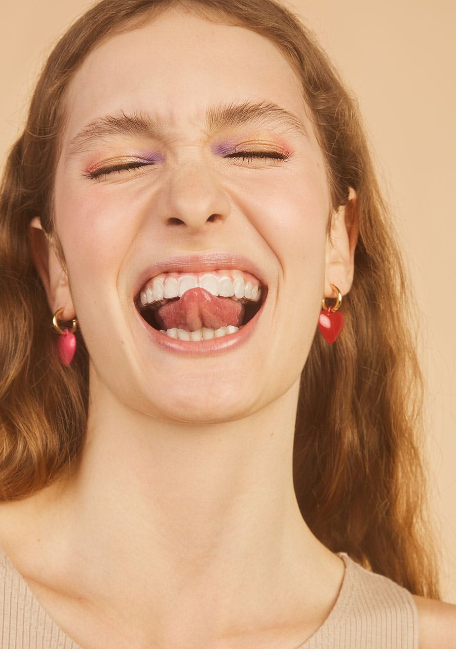 mulher sorrindo com a ponta da lingua para fora da boca